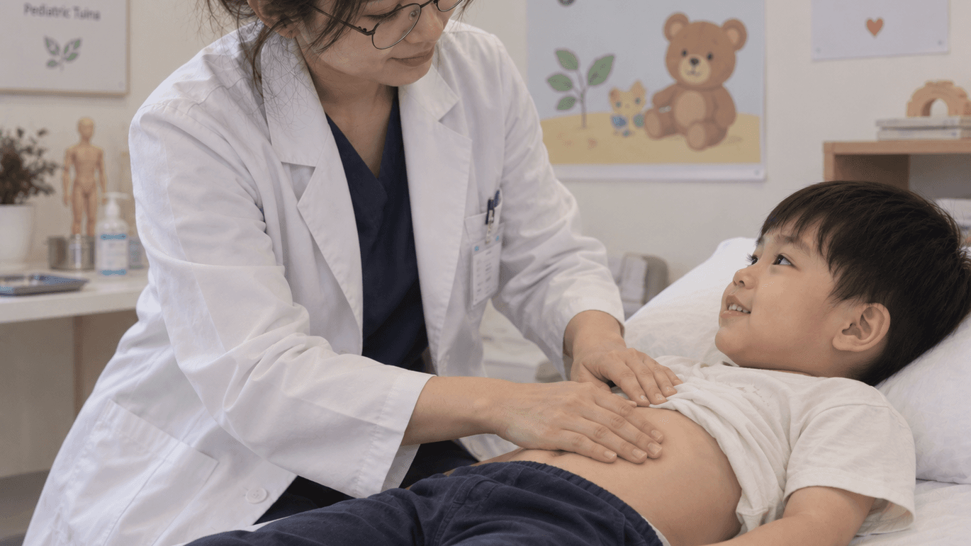 A physician in a white coat resting both hands on a young child's abdomen as the child lies on a treatment couch, looking up at her